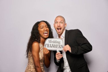 Kadın erkek poz veriyor ve elinde aksesuar var.