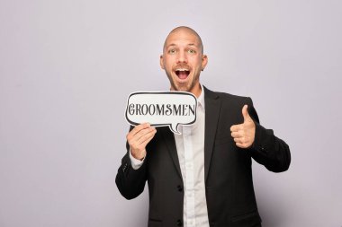 Erkek poz veriyor ve elinde aksesuar var.