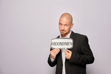 Erkek poz veriyor ve elinde aksesuar var.