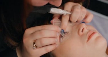 Lashmaker, güzellik salonundaki müşteriye kirpik temizleme prosedürünü yapar, kirpikleri uzatır, kozmetik hizmetleri, 4k 60p Prores HQ