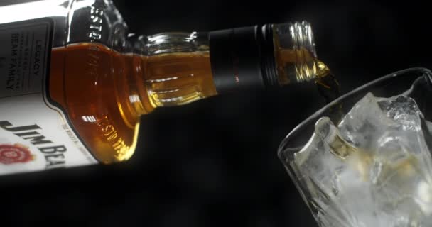 POLAND - 10 EYLÜL 2021: Jim Beam kokteyl bardağına ağır çekimde buzla dolduruluyor, alkol içeceği, 4k Prores 120 fps — Stok video