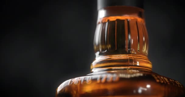 Close-up shot van de fles whisky die ronddraait op de donkere achtergrond, 4k 60p Prores HQ — Stockvideo