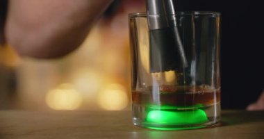Barmen, bar tezgahındaki kokteyl bardağındaki yumru shugarayı ezmek için Mudler kullanıyor. Kokteyl kuyruğunu barda yapıyor, 4k Prores HQ.