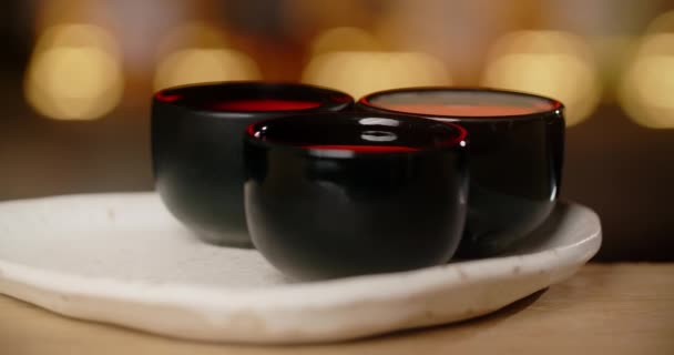 Barmen suşi çubuklarıyla zencefilli bir porselen bardakta tentür, Japon mutfağı restoranındaki barın tezgahında porselen shot, 4k 120 fps Prat 's HQ. — Stok video