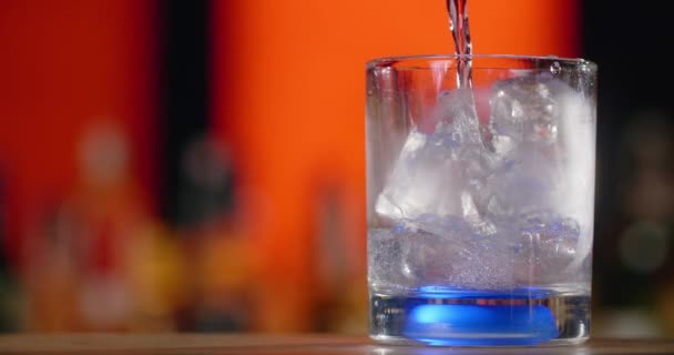 Barman ρίχνει διαφανές υγρό στο ποτήρι κοκτέιλ με παγάκια σε αργή κίνηση, κάνοντας το κοκτέιλ στον πάγκο μπαρ, 4k Prores HQ 120 fps — Αρχείο Βίντεο