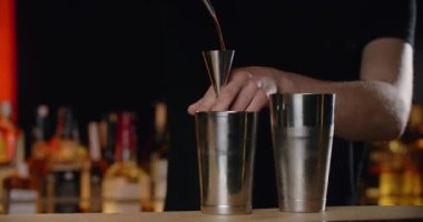 Barmen şeffaf alkolün bir kısmını jigger 'dan titreticiye yavaş çekimde doldurur, bu da kokteyli bar tezgahında yapar, 4k Prores 120 fps