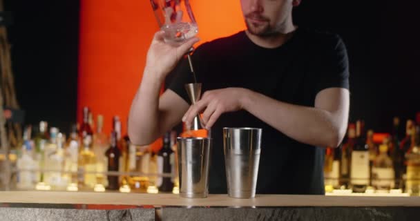 Barman pours portion of transparent alcohol from jigger to the shaker in slow motion, making the cocktail at the bar counter, 4k Prores HQ 120 fps — Stock Video