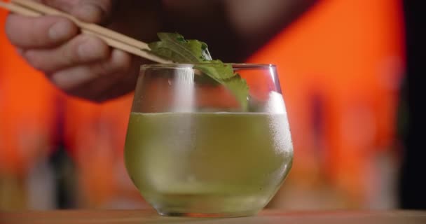 Barmann fügt frisches Shisoblatt zum Cocktailglas hinzu, macht den Cocktail mit asiatischem Perilla-Kraut, Barkeeper mixt kalte Getränke auf der Theke, 4k 120 fps Prores HQ — Stockvideo