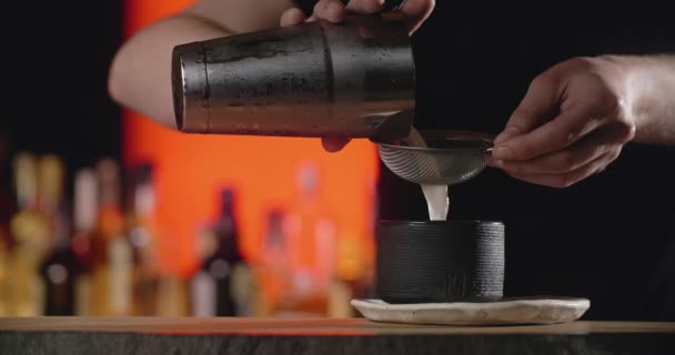Bartender menuangkan campuran koktail dari pengocok ke gelas tanah liat koktail beku melalui saringan dalam gerakan lambat, bartender membuat koktail dengan es dan minuman beralkohol campuran, 4k 120 fps Prores HQ — Stok Video