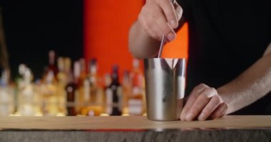 Barmen yavaşça barın tezgahındaki karıştırıcıyı karıştırır, gece kulübündeki alkollü içecek, 4k Prores 120fps