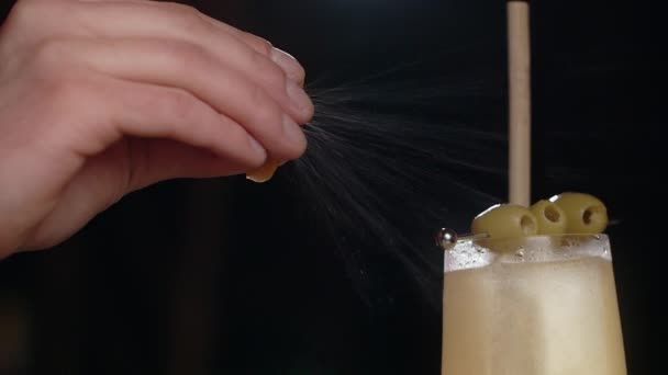 Barman squeezes citrus zest to the alcohol cocktail in slowmotion, splashes of essential oils from the peel, making the cocktail on bar counter, Full HD Prores HQ 240 fps — Stock Video