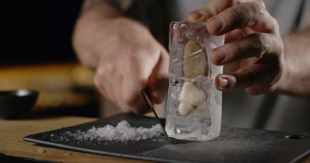 Cantinero hace hielo triturado de gran cubo de hielo por cuchillo afilado, haciendo el cóctel en el mostrador del bar, refrescantes bebidas frías, 4k Prores HQ 120fps — Vídeos de Stock