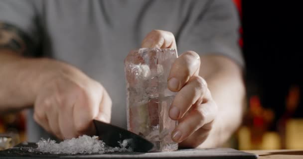 Bartender makes crushed ice from large ice cube by sharp knife, making the cocktail on the bar counter, refreshing cold drinks, 4k Prores HQ 120fps — Stock Video