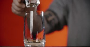 Barmen, dondurulmuş kokteyl bardağına forseps ile büyük buz küpü koyar, bu da kokteyli tezgahta yapar, 4k Prores HQ.