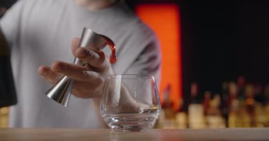 Barmen jigger 'dan kokteyl bardağına kadar alkolün bir kısmını ağır çekimde doldurur. Gece kulübünde kokteylleri yapar. 4k Prores HQ 120 fps.