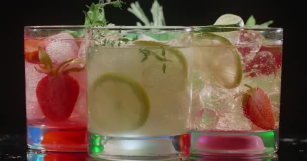 Cocktailglazen met kleurrijke cocktails draaien langzaam op de donkere achtergrond, alcoholische dranken en drank, alcoholvrije cocktail, objectvideo van limonade, 4k Prores HQ — Stockvideo