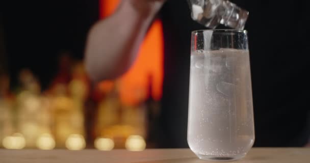 El camarero agrega cubitos de hielo al vaso con bebida refrescante en cámara lenta, haciendo que la limonada en el mostrador de la barra, 4k Prores HQ 120 fps — Vídeo de stock