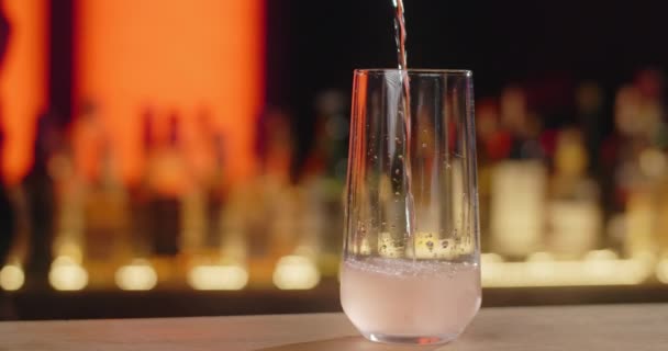 Barman schenkt transparante sprankelende drank in slow motion op het cocktailglas, waardoor de cocktail in de bar, 4k Prores HQ 120 fps — Stockvideo