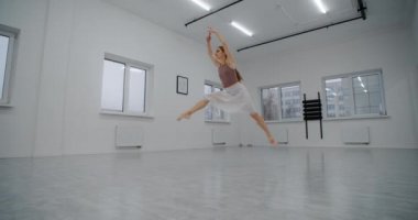 Sivri uçlu ayakkabılı balerin dans odasında koşar ve yavaş çekimde birkaç kez zıplar, dans eder ve havada sicim sallar, akrobatik dans eder, 4k 120 fps Prores Karargahı 10 bit