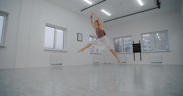 Ballerina in puntschoenen loopt door de danszaal en springt meerdere malen in slow motion, dansprongen en doet twine in de lucht, acrobatische dans, 4k 120fps Prores HQ 10 bit — Stockvideo