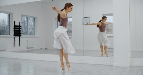 Bailarina en zapatos puntiagudos salta varias veces en cámara lenta frente a la pared del espejo de la sala de baile, bailarina salta y se enrolla en el aire, danza acrobática, 4k 120fps Prores HQ 10 bit — Vídeos de Stock