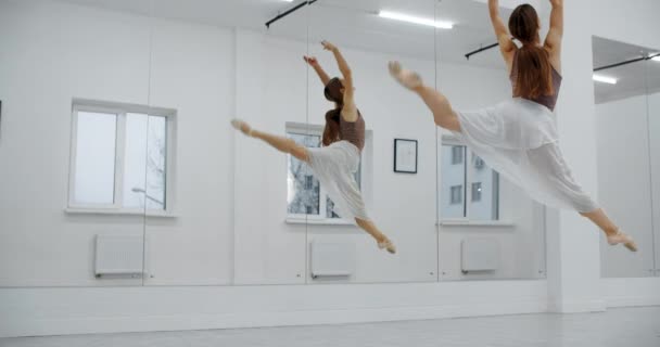 Ballerina in Spitzenschuhen springt mehrmals in Zeitlupe vor die Spiegelwand, tanzt springt und windet sich in der Luft, akrobatischer Tanz, 4k 120fps Prores HQ 10 bit — Stockvideo