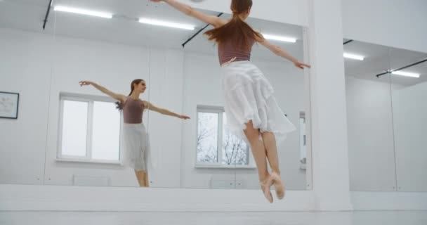 Sivri uçlu ayakkabılı balerin dans salonunun ayna duvarının önünde yavaş çekimde birkaç kez zıplar, dansçı zıplar ve havada sicim sallar, akrobatik dans eder, 4k 120fps Prores HQ 10 bit — Stok video