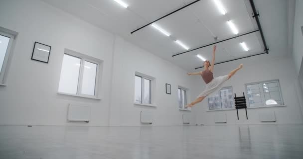 A bailarina em sapatos pontiagudos atravessa a sala de dança e salta várias vezes em câmera lenta, dança salta e corta no ar, dança acrobática, 4k 120fps Prores HQ 10 bit — Vídeo de Stock