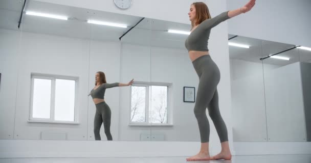 Jimnastikçi, beyaz salonun ayna duvarının önüne atlıyor. Beyaz salonda jimnastik, yoga ve pilates eğitmeni, 4k 120p Prores HQ. — Stok video