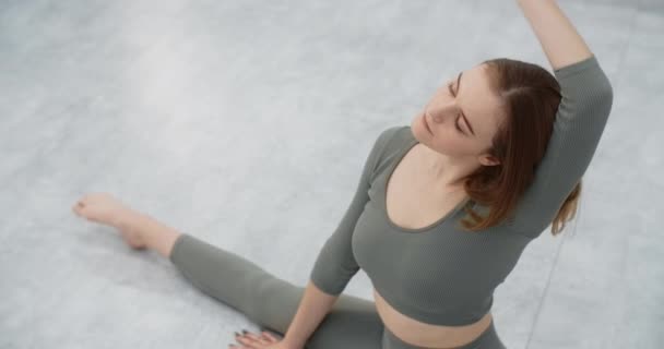 Yoga trainer voert zijwaartse bochten zittend op een touw, gymnastiek vrouw met strakke lichaam bochten doet pilates en stretching oefeningen op de vloer, yoga en pilates training, 4k 120p Prores HQ — Stockvideo