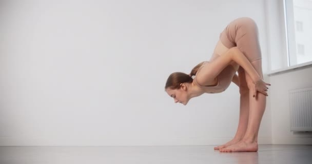 A jóga oktató nyújtási gyakorlatokat végez lassított felvételen, a torna nő feszes testgörbével pilates és jóga gyakorlatokat végez fehér alapon, 4k 120p Prores HQ — Stock videók