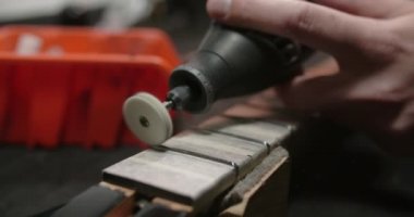 Luthier, müzik aletleri tamirhanesinde, 4k 60fps Prores karargahında gitar fretboardunda yeni perdeler parlatıyor.