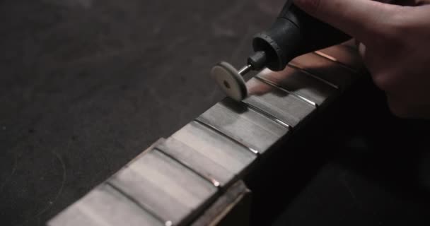 Лютьє полірує нові фризи на гітарній дошці в майстерні по ремонту музичних інструментів, 4k 60fps Prores HQ — стокове відео