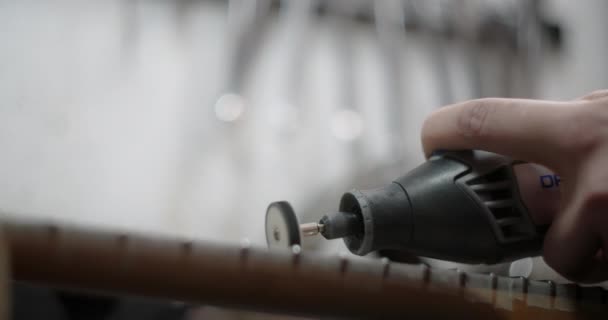 Luthier polijst nieuwe frets op de gitaar toets bij muziekinstrumenten reparatiewerkplaats, 4k 60fps Prores HQ — Stockvideo