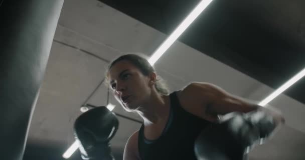 Женщина кикбоксер в боксерских перчатках удары боксерская сумка в замедленной съемке, обучение в боксерском клубе, 4k 60p Прорес HQ — стоковое видео
