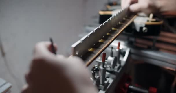 Luthier justerar fretboardvinkeln i elgitarren monterad på jiggen, reparera musikinstrumenten i hte butiken, 4k 60p 10 bit — Stockvideo