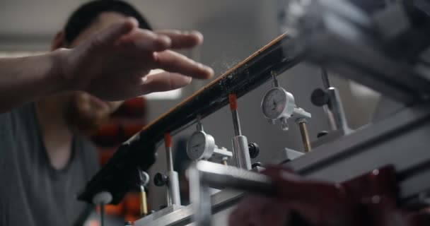 Luthier brosse la poussière de bois du cou de guitare poncée, travaille à l'atelier de réparation d'instruments de musique, 4k 60p 10 bits — Video