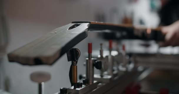 Лютер'єр встановлює електрогітару на джизі в музичному магазині ремонту інструментів, 4k 60p 10 біт. — стокове відео