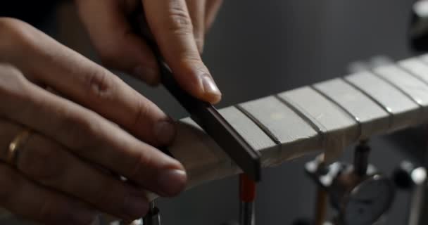 Luthier slijpt gitaar frets bij muziekinstrumenten reparatiewerkplaats, 4k 60fps 10 bit — Stockvideo
