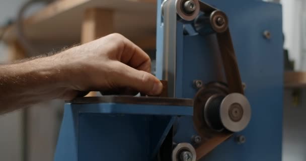 Ξυλουργός χρησιμοποιεί τριβείο ζώνης στο εργαστήριό του για την επεξεργασία των μικρών αντικειμένων ξυλείας, 4k 60p 10 bit — Αρχείο Βίντεο