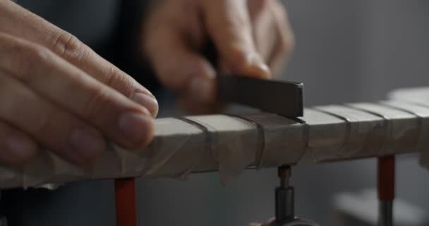 Luthier slijpt gitaar frets bij muziekinstrumenten reparatiewerkplaats, 4k 60fps 10 bit — Stockvideo