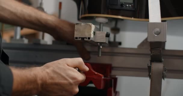 Luthier monterar den akustiska gitarren på jiggen vid musikinstrumentets reparationsverkstad, 4k 60p 10 bit — Stockvideo