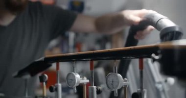 Gitar teknisyeni elektrikli süpürge kullanıyor. Zımparaladıktan sonra gitar boynundaki odun tozunu çıkarmak için. Müzik aletleri tamir dükkanı, 4K 60fps 10 bit.