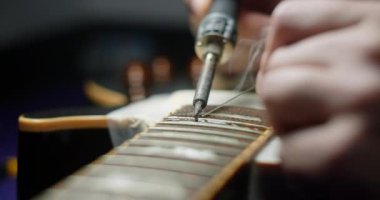 Luthier demir lehimleyerek gitarı ısıtıyor, gitar sanatçıları elektro gitarın frets değişimi için hazırlık yapıyorlar, 4k 60fps Prores HQ