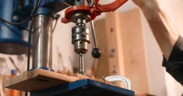 Ξυλουργός τρυπά τρύπες σε ξύλινη σανίδα με μηχανή γεώτρησης σε αργή κίνηση, ξυλουργική στο εργαστήριο, έφερε τις τρύπες, μηχανική επεξεργασία της ξυλείας, 4k DCI 60p Prores 422 HQ 10 bit — Αρχείο Βίντεο