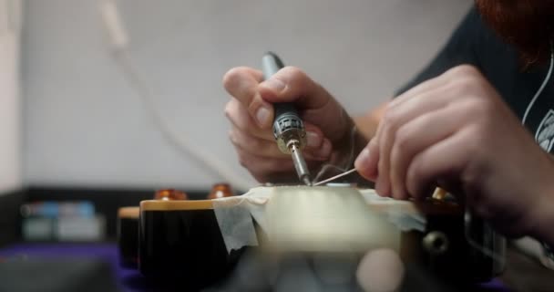 Luthier calienta trastes en la guitarra por el soldador antes de refretting, preparaciones de los artesanos de la guitarra para el reemplazo de trastes en la guitarra eléctrica, 4k 60fps Prores HQ — Vídeo de stock