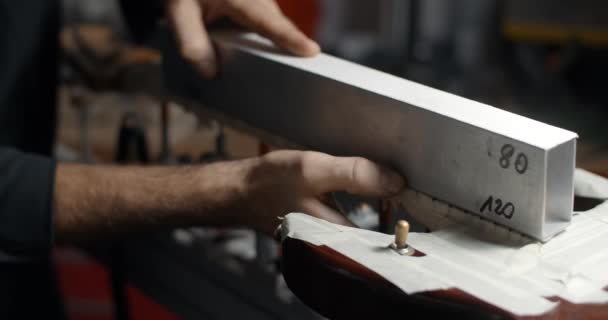 Luthier arenas trastes guitarra en taller de reparación de instrumentos musicales, 4k 60fps 10 bit — Vídeo de stock