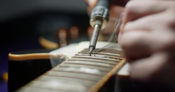 Luthier podgrzewa progi na gitarze przez lutowanie żelaza przed refretting, gitara rzemieślników preparaty do wymiany progi w gitarze elektrycznej, 4k 60fps Prores HQ — Wideo stockowe