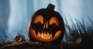 Cadılar Bayramı balkabağı suratlı ve mumları olan gece karanlık rüzgarlı bir ormanda duruyor, 4k 60p Prores Karargahı 10 bit