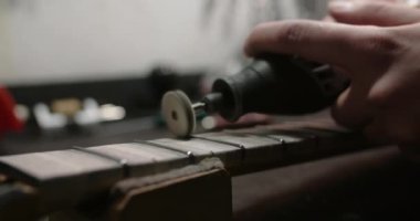 Luthier, müzik aletleri tamirhanesinde, 4k 60fps Prores karargahında gitar fretboardunda yeni perdeler parlatıyor.